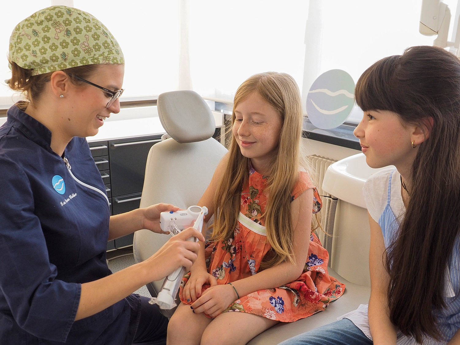 Un'igenista dentale dello studio insegna a due bambine come lavarsi i denti